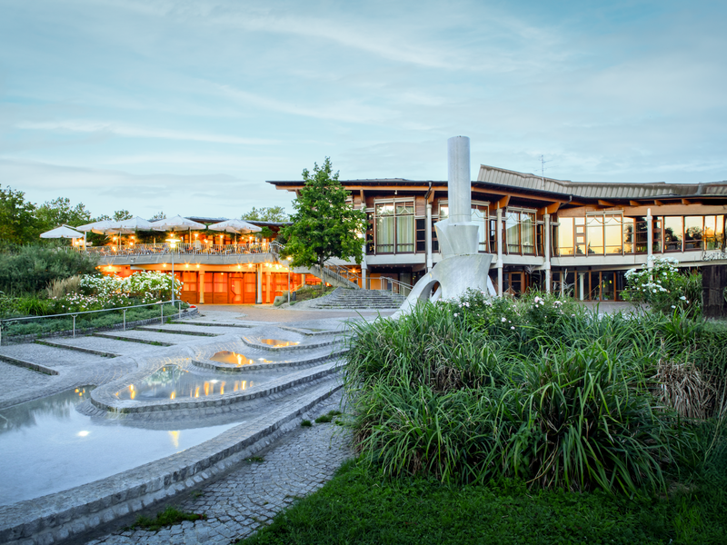 Das Bürgerzentrum Waiblingen bei Abenddämmerung. Im Vordergrund Wasserspiele und eine Skulptur.