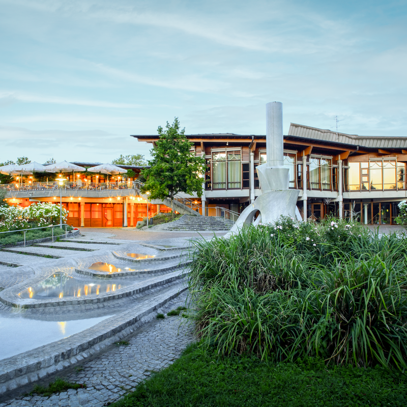 Das Bürgerzentrum Waiblingen bei Abenddämmerung. Im Vordergrund Wasserspiele und eine Skulptur.