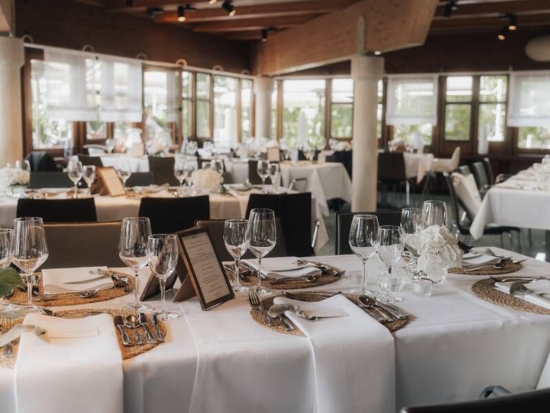 festlich eingedeckte Tische des Restaurants Remsstuben mit weißen Tischdecken und weißem Geschirr, siblernes Bestck und weißer Blumendeko