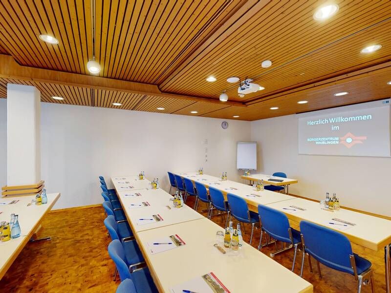 Schwabentreff in Seminarbetischung mit Holzboden, Holzdecke und blauen Stühlen. 