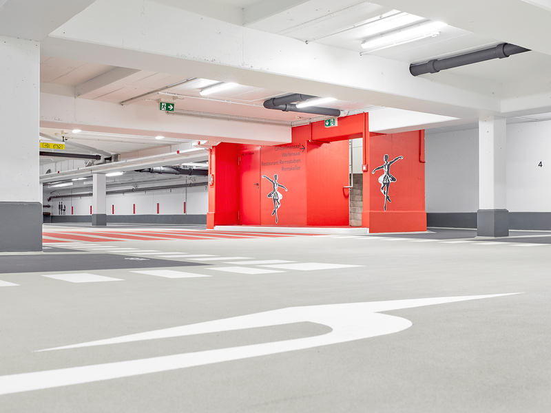 Auf dem Bild sieht man eine Tiefgarage mit Parkflächen sowie dem Treppenaufgang nach oben.