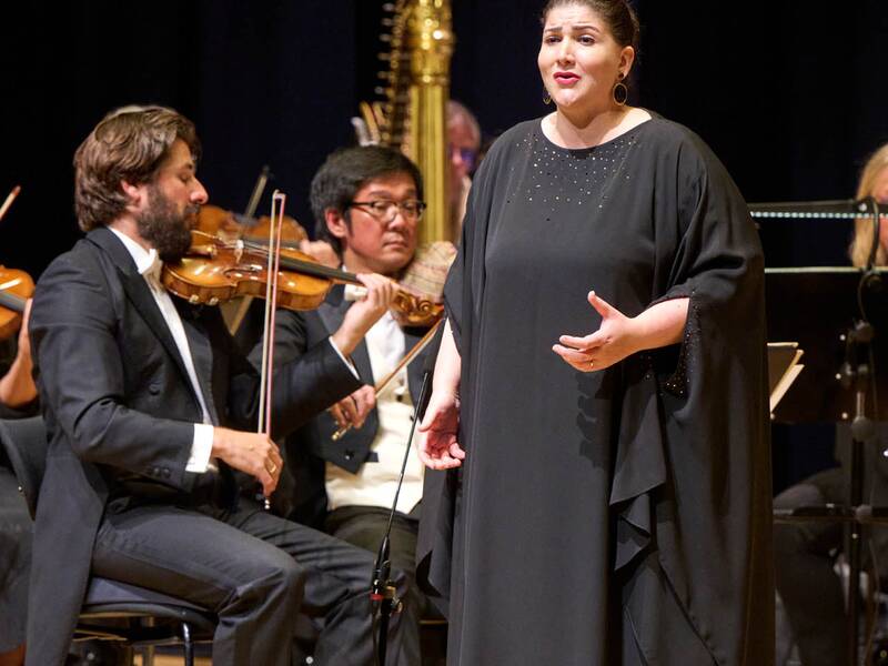 Eine Frau singt emotionsvoll im langen schwarzen Kleid